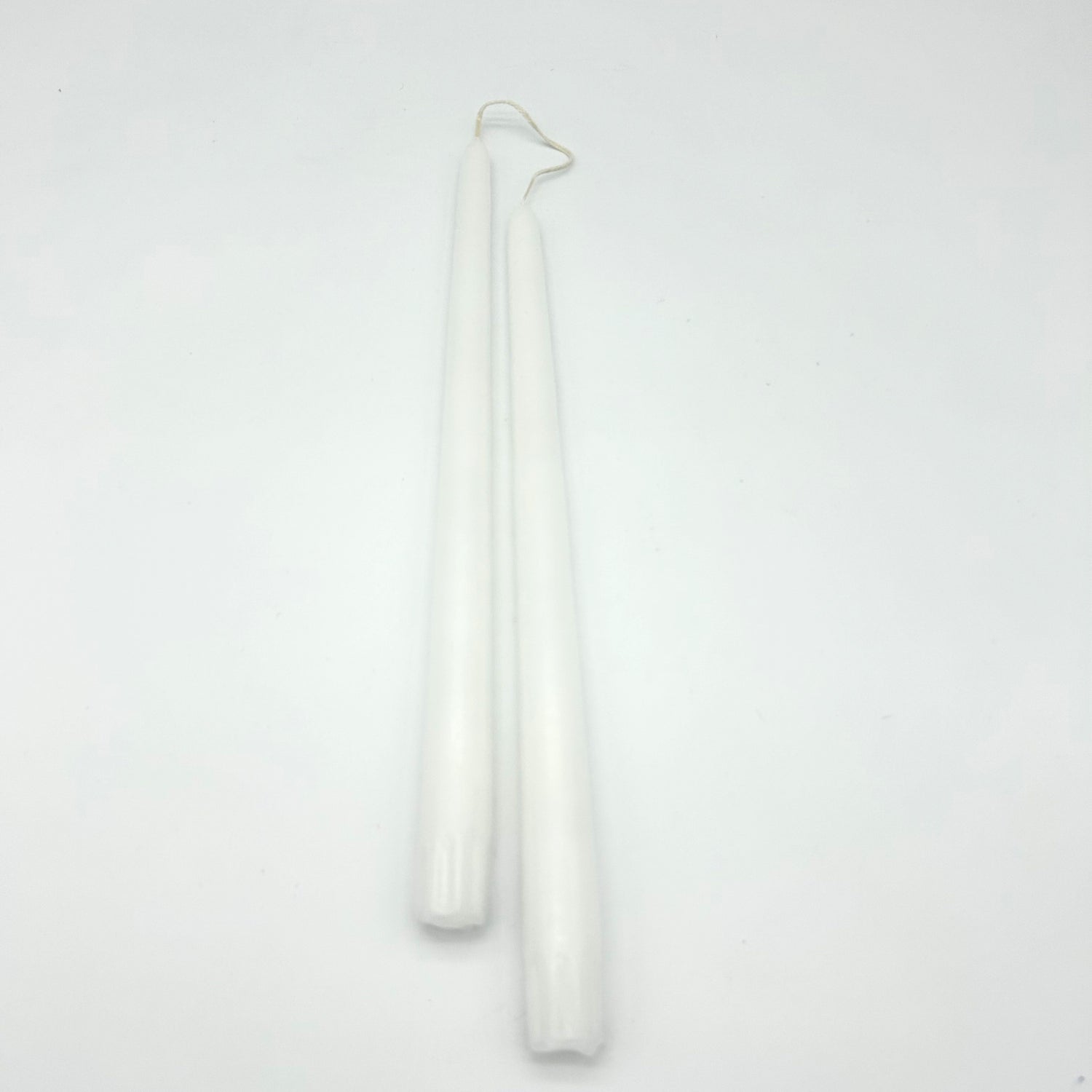 Two white candles on a light gray background